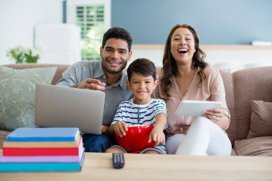 Happy family sitting together on the couch with their electronic devices